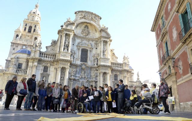 Un megalazo solidario amarillo en la Plaza Belluga para concienciar sobre la espina bífida